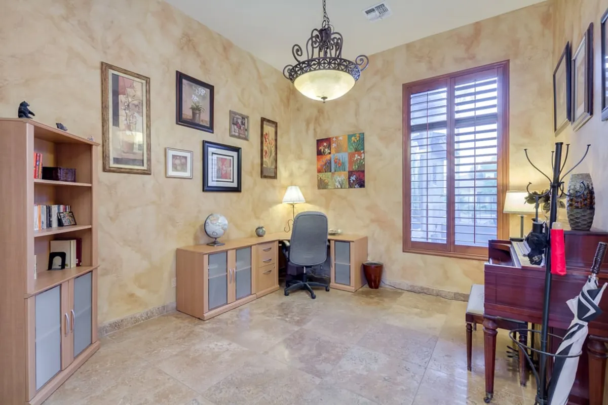 A dedicated office space with a desk and chair, bookshelf, piano, globe, and tasteful wall art. The room is arranged for productivity, creativity, and focus, evoking a calm and inspiring environment ideal for remote work or study.
