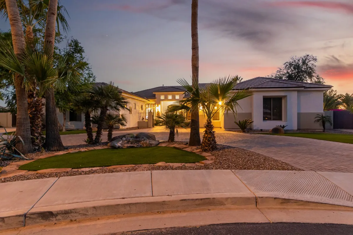 A welcoming exterior shot of the home's illuminated entrance surrounded by palm trees and a landscaped garden, creating an inviting first impression and reflecting the peaceful neighborhood setting ideal for remote work.