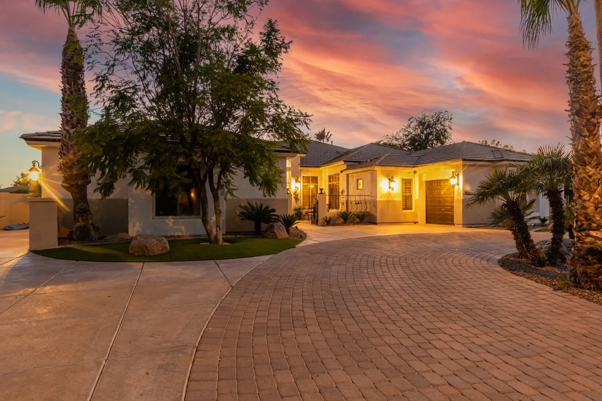 The front entrance of the property is warmly lit, framed by palm trees and a curved driveway. The welcoming exterior hints at a spacious, secure environment and serves as a first impression of a pet-friendly home base for exploring nearby parks and trails.